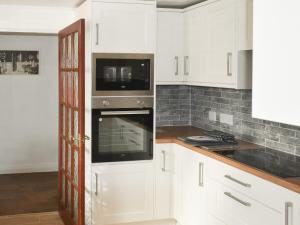 a kitchen with white cabinets and a microwave at Albion Cottage in Whitby