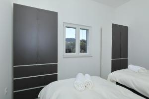 a white bedroom with two beds and a window at Kuca za odmor Davorka in Lukoran