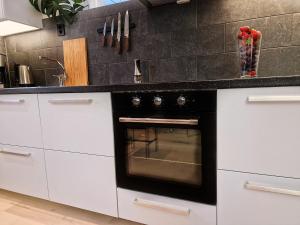 a black oven in a kitchen with white cabinets at Ibsens apartaments in Bergen