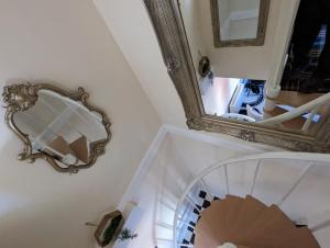 a mirror on the wall next to a spiral staircase at Flemingate Cottage, Beverley in Beverley
