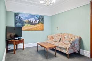 a living room with a couch and a tv and a table at Wellesley Boutique Hotel in Wellington