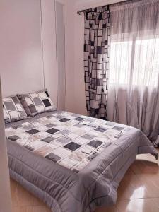 - une chambre avec un lit doté d'une couverture en damier et d'une fenêtre dans l'établissement Appartement Martil , très proche de la plage, à Martil
