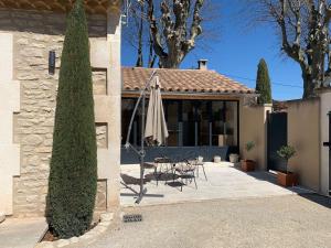 a house with a patio with a umbrella and a tree at Mazet Le Micocoulier in Saint-Rémy-de-Provence