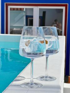 dos copas de vino sentadas en una mesa junto a una piscina en Pátio dos 8 - Alentejo, en Vale de Santiago