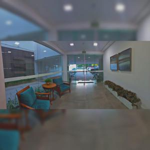 an office lobby with chairs and a table and windows at Hotel Conceição in Linhares