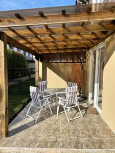 un patio con mesa y sillas bajo una pérgola de madera en Casa nueva en Pucón, en Pucón