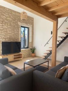 a living room with a couch and a tv and stairs at Mazet Le Micocoulier in Saint-Rémy-de-Provence