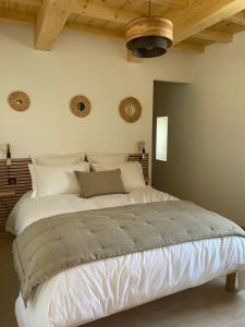 ein großes weißes Bett in einem Schlafzimmer mit Holzdecke in der Unterkunft Mazet Le Micocoulier in Saint-Rémy-de-Provence