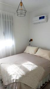 - une chambre blanche avec un grand lit et une fenêtre dans l'établissement Donado centro, à Bahía Blanca