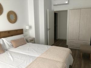 1 dormitorio con cama blanca y espejo en Puerta del Buey Apartamentos, en Niebla