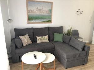 a living room with a gray couch and a white table at Puerta del Buey Apartamentos in Niebla