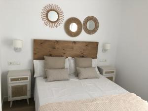 a bedroom with a large white bed and a mirror at Puerta del Buey Apartamentos in Niebla