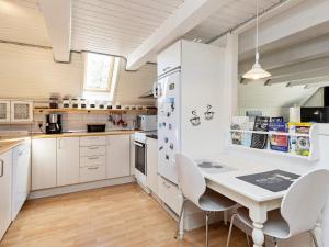 Holiday home Hals XIV في هالس: مطبخ مع دواليب بيضاء وطاولة وكراسي