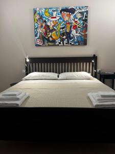 1 dormitorio con 1 cama con una pintura en la pared en Le spiagge di Avola: Casa della Musica, en Avola