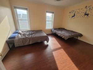 a bedroom with two beds and two windows at 4 Bedroom 3 bathroom 6 queen bed 5 full floor mattress with backyard Whole house for travel or vacation public and celebration group gatherings in Toronto