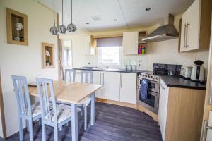 a kitchen with a wooden table and a table and chairs at Modern 6 Berth Caravan At Highfield Grange Near Clacton-on-sea Ref 26302e in Clacton-on-Sea