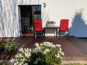una terraza con 2 sillas, una mesa y flores en Ferienwohnung OstseeStrandLäufer 3 en Zingst