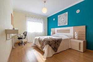 ein Schlafzimmer mit einem Bett und einer blauen Wand in der Unterkunft Apartamento Mãe Soberana in Loulé