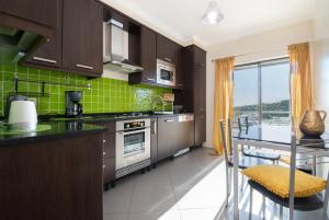 a kitchen with brown cabinets and a green tile wall at Apartamento Mãe Soberana in Loulé