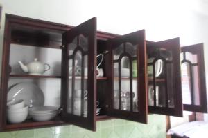 a wooden cabinet with plates and dishes in it at Raj Villa Kumarakanda Hikkaduwa in Hikkaduwa