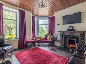 a living room with a fireplace and a red rug at Groudd Hall in Cerrigydrudion