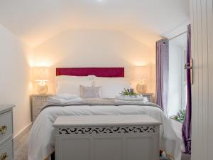a bedroom with a large white bed with a red headboard at Bwthyn Cerrigos in Milford Haven