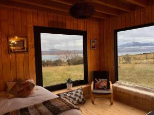 a bedroom with two windows and a bed and a chair at Casa Aoni in Puerto Natales