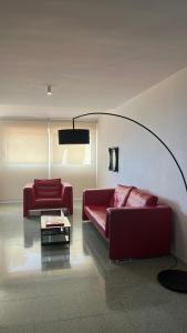 una sala de estar con 2 sofás rojos y una mesa. en VIP Alfaz del Pi, en Alfaz del Pi