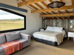 a bedroom with a bed and a couch and a window at Casa Aoni in Puerto Natales