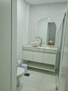 La salle de bains blanche est pourvue d'un lavabo et d'un miroir. dans l'établissement Estúdio 2 min Praia Copacabana - Área Nobre, à Rio de Janeiro
