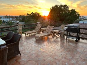 a grill and chairs on a patio with the sunset at Balcon Buenavista in Seville