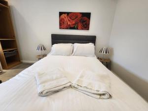 a bedroom with a white bed with white sheets and red roses at Hazel 1-Bed Flat (4) + Parking in Kidlington