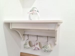 a white shelf with three tea cups on it at Apartment Mara&Padrona in Zadar