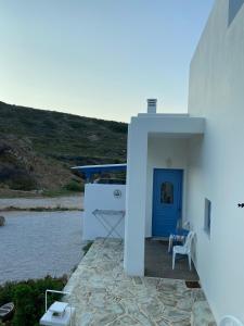 a white building with a blue door and chairs at Mpasales house in Skiros