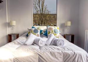- un lit blanc avec des oreillers et une fenêtre dans l'établissement Alto Labrador Apartment, à El Calafate