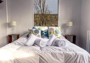 Cama blanca con almohadas y ventana en Alto Labrador Apartment en El Calafate