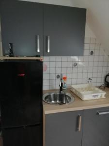 eine Küche mit einer Spüle und einem schwarzen Kühlschrank in der Unterkunft Möblierte Dachgeschosswohnung in ruhiger Lage zu vermieten in Wetzlar