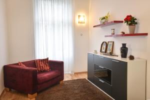 ein Wohnzimmer mit einem roten Stuhl und einem Kamin in der Unterkunft Be Inspired, Choose The Best! in Wien