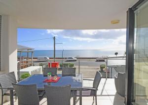 einen Tisch und Stühle auf einem Balkon mit Meerblick in der Unterkunft Luxurious Beachfront Apartment in Hervey Bay