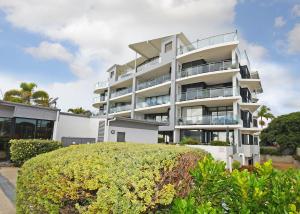 a white apartment building with a bush in front of it at Luxurious Beachfront Apartment in Hervey Bay
