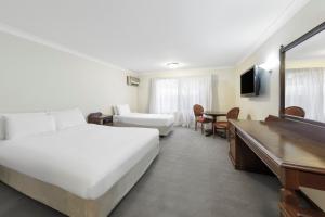 um quarto de hotel com uma cama e uma secretária em Elizabethan Lodge em Melbourne