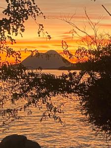 a sunset over a body of water with a mountain at La maison de la plage in Sainte-Luce
