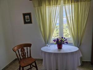 einen Tisch mit einer Vase aus Blumen und einem Fenster in der Unterkunft Villa Gabriel in Pag