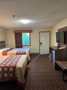 a hotel room with two beds and a flat screen tv at American Inn in Branford