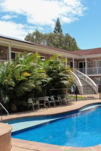 a hotel with a swimming pool with chairs and a staircase at Aston Motel Yamba in Yamba