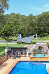 a swimming pool with a picnic table and a canopy over it at Aston Motel Yamba in Yamba