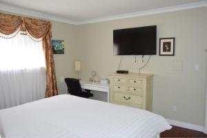 um quarto com uma cama, uma secretária e uma televisão em Jane's private rooms with shared washroom em Surrey