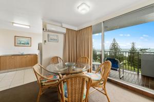 a dining room with a glass table and chairs and a balcony at Sandpiper Broadbeach in Gold Coast
