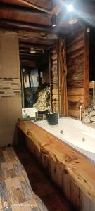 bañera en una habitación con pared de madera en Cabaña en el Árbol La Calera, en La Calera