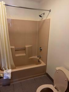 a bathroom with a shower and a toilet and a tub at American Inn in Branford